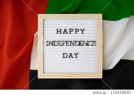 HAPPY INDEPENDENCE DAY text frame on United Arab Emirates waving flag made from silk material. Commemoration Day Muslim Public holiday celebration background. The National Flag of UAE 119819020