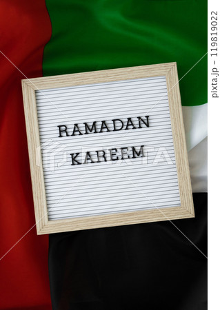 Congratulations with text RAMADAN KAREEM - happy holidays waving UAE flag on background concept. Commemoration Day Muslim Greeting card advertisement. Blessed holy month holiday 119819022