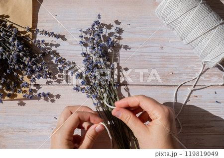 Top view flat lay of process making bouquets of dried lavender flowers. Cotton rope, scissors. Female do homemade herbs bouquet Top view flat lay of process making bouquets of dried lavender flowers. Cotton rope, scissors. Female do homemade herbs bouquet 119819049