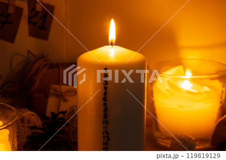 Candle with advent calendar Traditional Burning Christmas Wax Candles with numbers counting down for Christmas. Beautiful Advent At Home. Festive Candlelight And Dark Background Candle with advent calendar Traditional Burning Christmas Wax Candles with numbers counting down for Christmas. Beautiful Advent At Home. Festive Candlelight And Dark Background 119819129