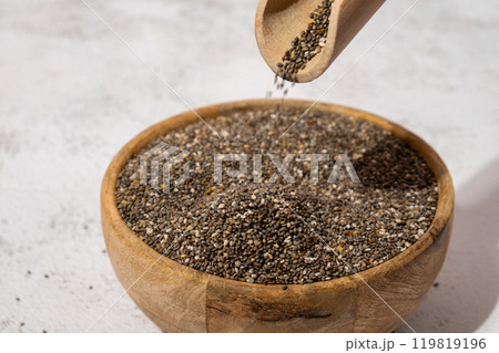 Chia seeds fall in wooden bowl. Healthy superfood rich in Omega 3 fatty acids. Dry healthy natural ingredient. Chia grains are falling 119819196