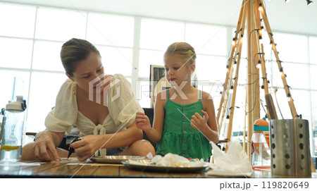 Mother and her daughter paint Halloween cookies  119820649
