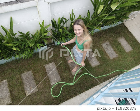 A young woman waters her beautiful garden 119820878