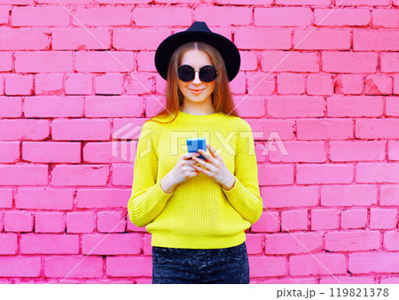 Stylish modern young woman with smartphone, teenage girl holding phone on colorful pink background 119821378
