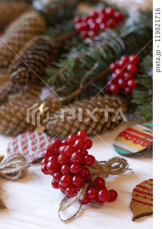 DIY decorations for Christmas. Rural style Christmas with eco-conscious details: snowball tree, cones and wooden handmade decorations for the Xmas tree on pine branches. New Year natural wooden toys. 119821716