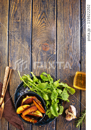 Baked potato wedges with addition sea salt and rucola on wooden background 119822202