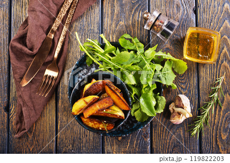Baked potato wedges with addition sea salt and rucola on wooden background 119822203