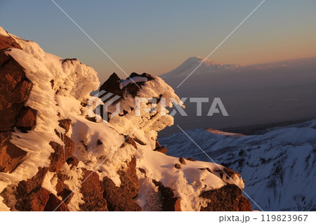 Breathtaking view of a snowy mountain peak surrounded by rocky terrain and clear blue skies at dawn Breathtaking view of a snowy mountain peak surrounded by rocky terrain and clear blue skies at dawn 119823967