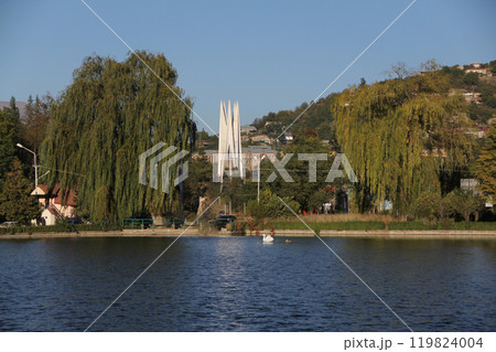 Lakeside view with willow trees and distant white monument on a hill. Lakeside view with willow trees and distant white monument on a hill. 119824004