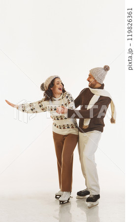 Cheerful stylish couple in cozy and warm winter outfits ice skating together, having fun and joy during winter vacation. isolated on white background Cheerful stylish couple in cozy and warm winter outfits ice skating together, having fun and joy during winter vacation. isolated on white background 119826361