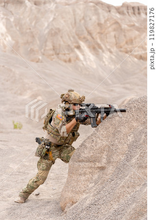 Vertical image of military or soldier with hold gun and stand in postition fighting in battlefield with near the mountain during outdoor practice. Vertical image of military or soldier with hold gun and stand in postition fighting in battlefield with near the mountain during outdoor practice. 119827176