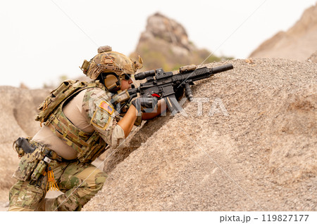Close up military or soldier with hold gun and stand in postition fighting in battlefield with near the mountain during outdoor practice. Close up military or soldier with hold gun and stand in postition fighting in battlefield with near the mountain during outdoor practice. 119827177