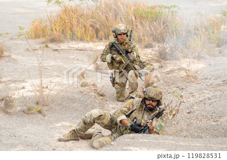 One of soldier or military lie down and look at camera and the other one sit in the position of ready to fighting during outdoor practice. 119828531
