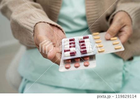 Asian elderly woman holding pill drug in hand, strong healthy medical concept. Asian elderly woman holding pill drug in hand, strong healthy medical concept. 119829114