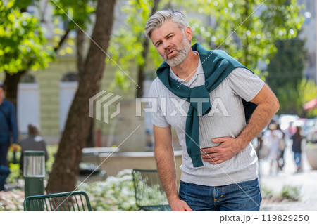 Mature man feeling sudden strong abdominal stomach ache gastritis problem poisoning diarrhea outdoor 119829250