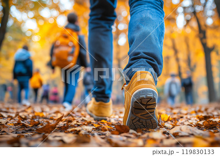 Family walking in autumn park. Tourists walking in the autumn forest. Feet close-up. Traveling, family vacations and fall seasonal holidays concept 119830133