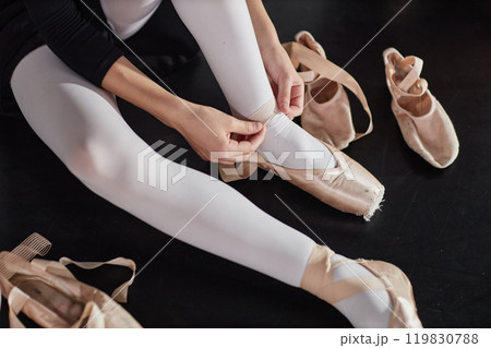 Cropped shot of teenage girl putting on satin ballet shoes with elastic bands preparing for class while sitting on floor in dance studio, copy space Cropped shot of teenage girl putting on satin ballet shoes with elastic bands preparing for class while sitting on floor in dance studio, copy space 119830788