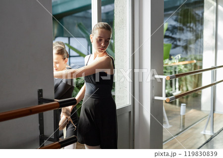 Medium full shot of tired looking young ballerina walking into practice room at start of dance class in studio, copy space 119830839