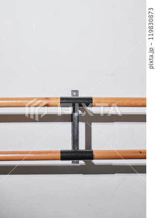 Vertical shot of professional barre for practicing ballet positions and stretching in empty dance studio against white wall, camera flash, copy space Vertical shot of professional barre for practicing ballet positions and stretching in empty dance studio against white wall, camera flash, copy space 119830873