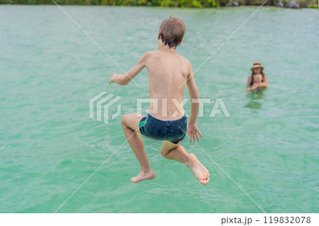 Mother with her teenage and toddler sons swimming in the turquoise waters of Lake Bacalar. Family bonding, summer vacation, and outdoor fun in Quintana Roo, Mexico concept 119832078