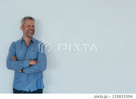 Young professional wearing a blue shirt,standing against, white background with arms crossed 119833304