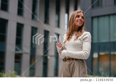A Confident Young Woman with a Laptop Posing in a Modern Urban Environment Setting 119833650