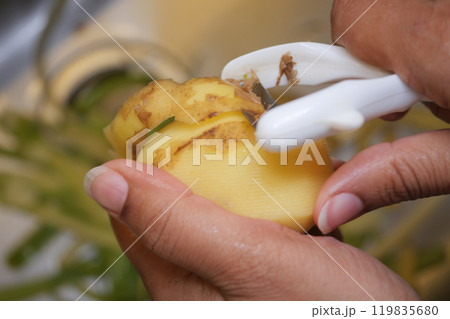 Peeling a Fresh, Delicious Potato in the Kitchen for Cooking Amazing Meals and Recipes 119835680