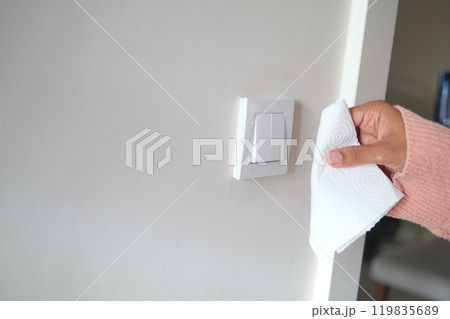 woman hand with tissue wiping a light switch at the wall woman hand with tissue wiping a light switch at the wall 119835689