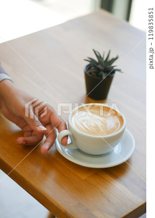 A Stylish Coffee Cup Resting on a Wooden Table, Accompanied by a Small Healthy Plant 119835851