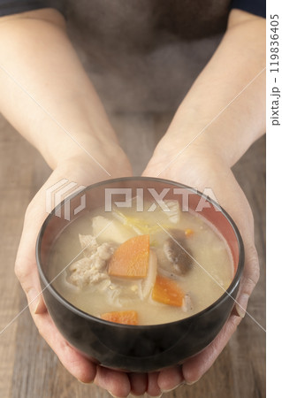 湯気の立つ味噌汁を手で持つ　配膳する 119836405