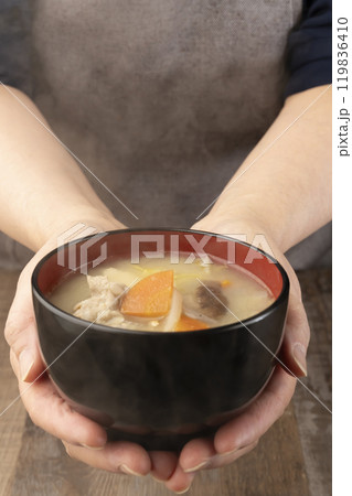 湯気の立つ味噌汁を手で持つ　配膳する 119836410
