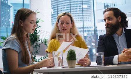 Parent and child looking over personalized planning guide written by financial advisor during meeting. Consultant optimizing spending habits of clients requesting help, camera A 119837522