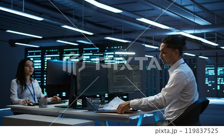 System administrator in data center maintaining accurate paperwork of hardware, generating reports. IT expert in high tech server farm doing workplace disaster recovery planning, camera B 119837525