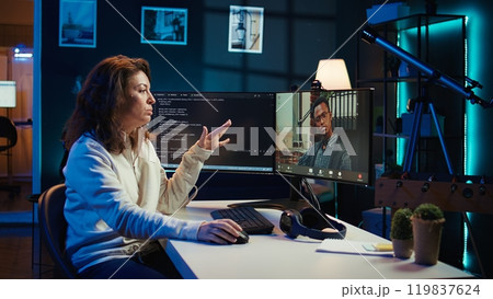 Woman doing software debugging helped by coworker in videocall, checking errors in lines of code. Programmer working from home fixing coding mistakes, assisted by colleague in teleconference, camera B Woman doing software debugging helped by coworker in videocall, checking errors in lines of code. Programmer working from home fixing coding mistakes, assisted by colleague in teleconference, camera B 119837624