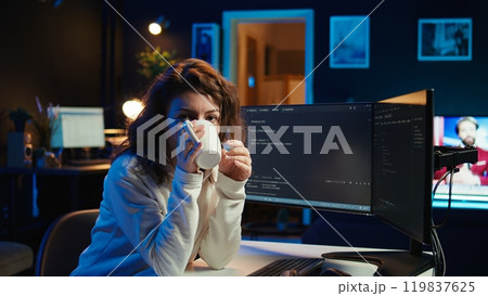Portrait of happy computer engineer enjoying hot tea while implementing security measures to protect company systems and data. Joyful IT worker holding coffee mug and debugging code, camera B Portrait of happy computer engineer enjoying hot tea while implementing security measures to protect company systems and data. Joyful IT worker holding coffee mug and debugging code, camera B 119837625
