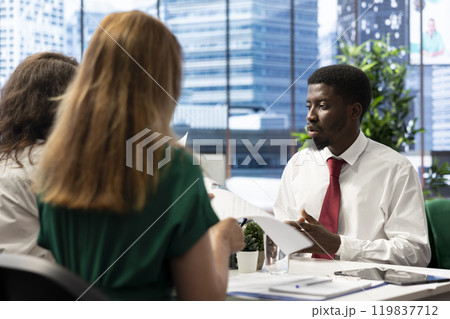 Human resources department team holding applicant CV, sitting at office desk during meeting. HR employer colleagues selecting candidates to work for organization, reading resume 119837712