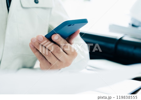 スマホを操作する作業着の男性 スマホを操作する作業着の男性 119838555