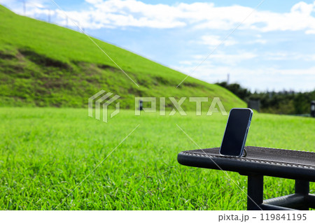 公園のベンチに置かれたスマートフォン 119841195