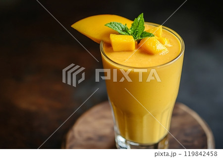 A detailed shot of a rich, creamy mango lassi in a tall glass, topped with a slice of fresh mango 119842458