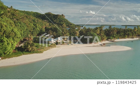 Aerial flight over bungalows houses on private small beach. Crystal water, white sand, palm trees, green hill landscape. Remote wild nature tropical island paradise, exotic vacation summer travel Aerial flight over bungalows houses on private small beach. Crystal water, white sand, palm trees, green hill landscape. Remote wild nature tropical island paradise, exotic vacation summer travel 119843425