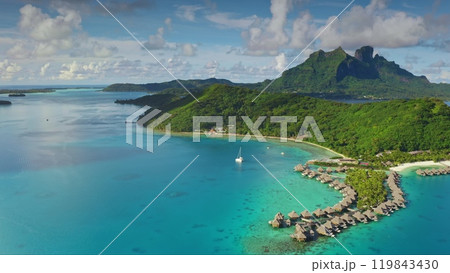 Turquoise lagoon water, overwater bungalows and green hills mountains of Bora Bora tropical island in French Polynesia. Remote wild nature exotic summer vacation travel background. Drone aerial shot 119843430