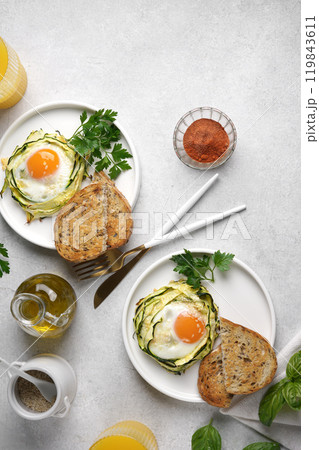 Two plates with fried eggs in zucchini noodle nests with sesame and juice in glass, healthy breakfast, top vertical view, copy space 119843611