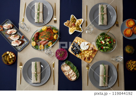 Flat lay of festive dishes with roasted chicken as main course and plates with napkins decorated with tiny fir branches served on christmas dining table 119844192