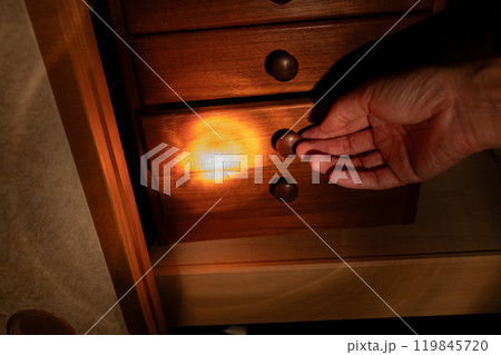 夜中の暗い部屋でたんすの引き出しを開ける 夜中の暗い部屋でたんすの引き出しを開ける 119845720