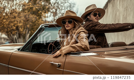 クラシックカーでポーズを取る帽子にサングラスの男女 119847235
