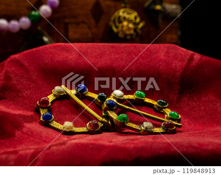 shot of a pair of golden brooches with gems for medieval antique clothing used for decoration on red velvet shot of a pair of golden brooches with gems for medieval antique clothing used for decoration on red velvet 119848913
