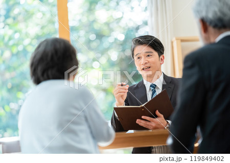 シニア夫婦に説明する営業マン 遺産相続について相談するシニア夫婦 シニア夫婦に説明する営業マン 遺産相続について相談するシニア夫婦 119849402