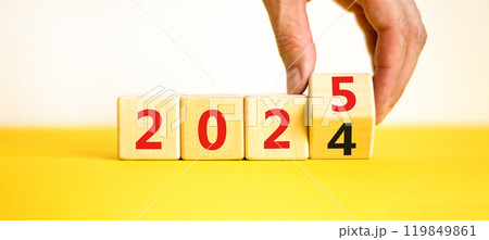 Business concept of 2025 new year symbol. Beautiful turned wooden cube and changed number 2024 to 2025. Beautiful yellow table white background, copy space. Business 2025 happy new year concept. Business concept of 2025 new year symbol. Beautiful turned wooden cube and changed number 2024 to 2025. Beautiful yellow table white background, copy space. Business 2025 happy new year concept. 119849861