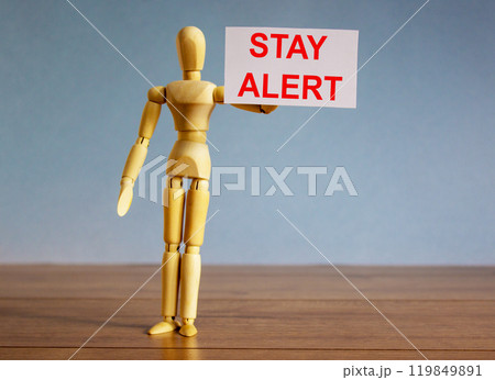 Wooden model of a man holding a tablet saying 'stay alert'. COVID-19 pandemic concept. Wooden model of a man holding a tablet saying 'stay alert'. COVID-19 pandemic concept. 119849891
