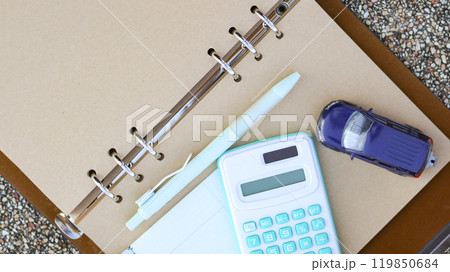 Model car a pen and a calculator are on notebook with blur background. Planning of saving for buying car, car loan and car insurance concept. 119850684